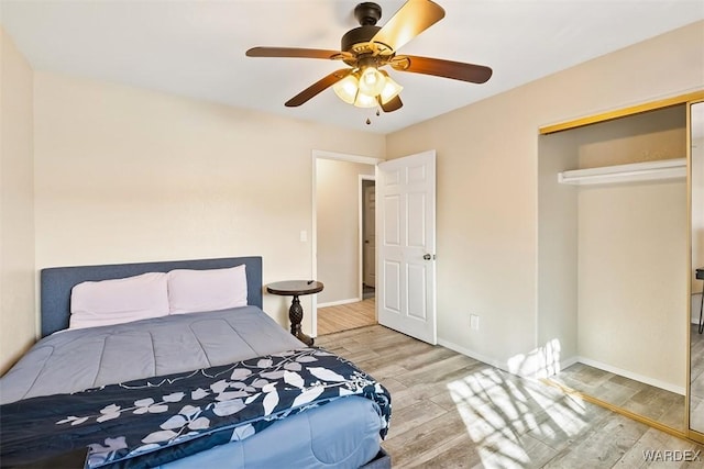 bedroom with a closet, wood finished floors, a ceiling fan, and baseboards