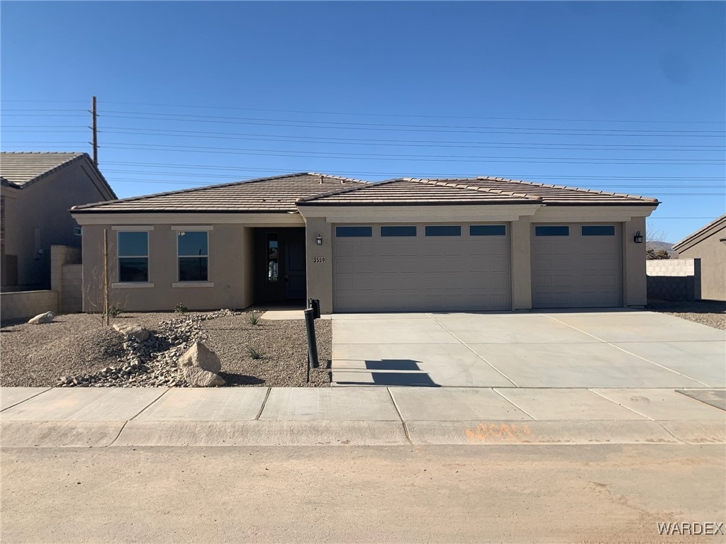 view of front of house with a garage, driveway, a tiled roof, and stucco siding