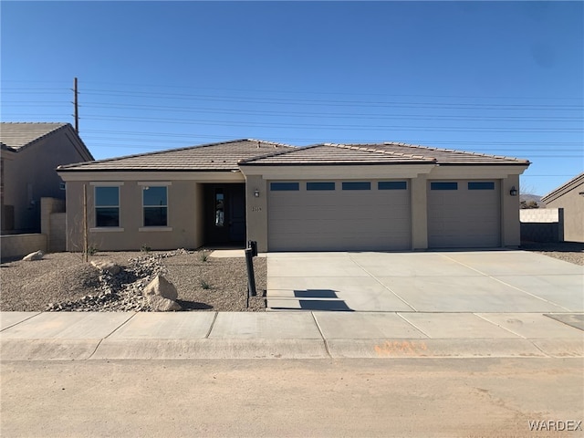 view of front of house with a garage, driveway, a tiled roof, and stucco siding