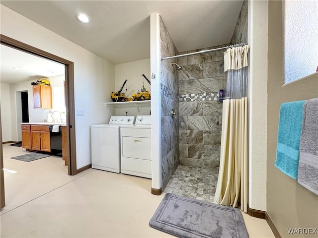 full bathroom with vanity, baseboards, tiled shower, separate washer and dryer, and concrete flooring