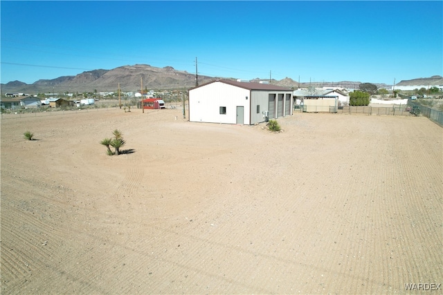 view of yard featuring an outbuilding, fence, and a mountain view