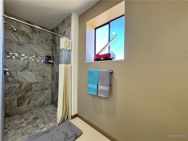 full bathroom featuring a shower stall and baseboards