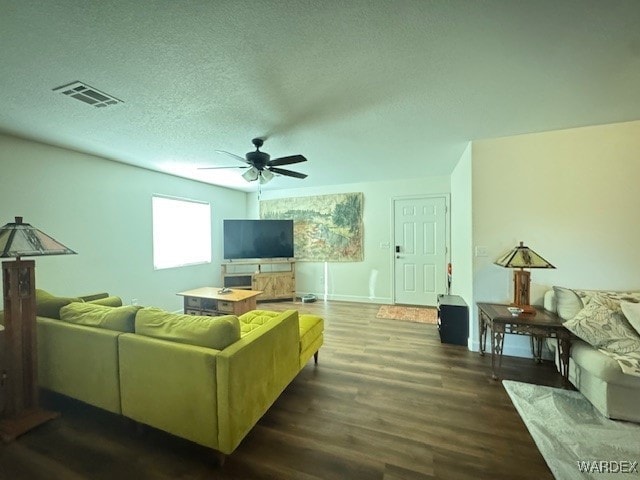 living room with dark wood finished floors, visible vents, a ceiling fan, a textured ceiling, and baseboards