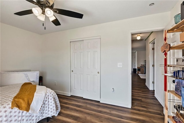 bedroom with dark wood-type flooring, a closet, ceiling fan, and baseboards