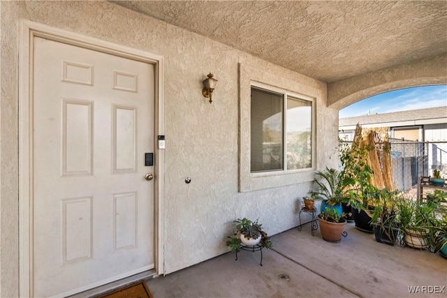 property entrance featuring fence and stucco siding