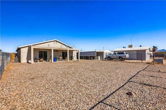 rear view of property with central AC unit, a patio area, and fence