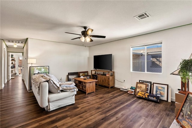 living room featuring ceiling fan, visible vents, and dark wood-type flooring