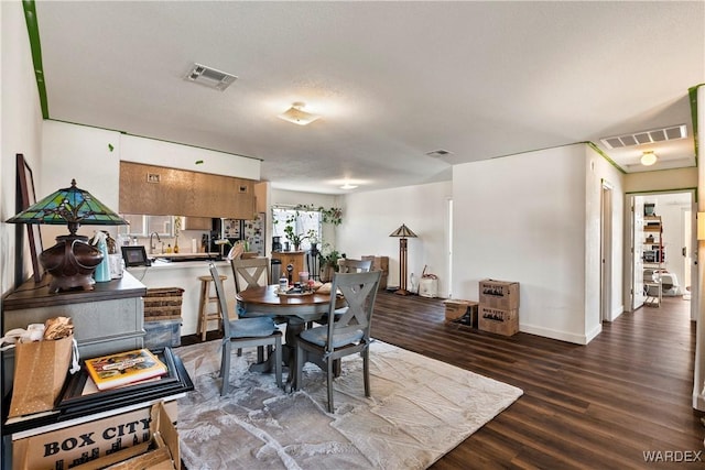 dining space with baseboards, visible vents, and wood finished floors