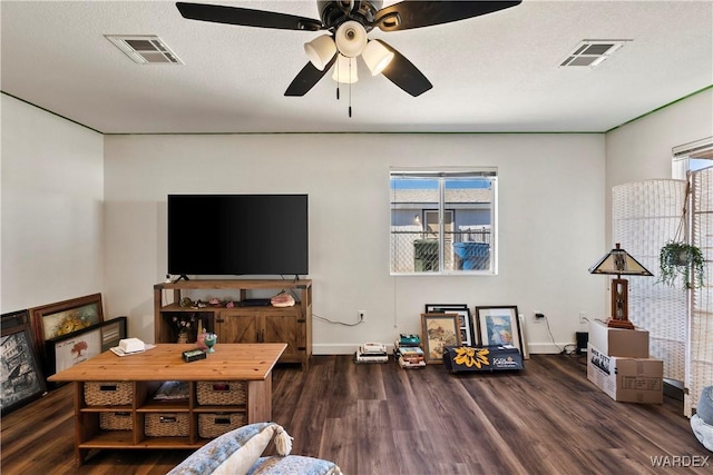 living area featuring a textured ceiling, dark wood-style flooring, visible vents, and baseboards