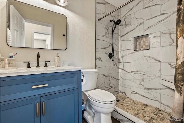 bathroom featuring toilet, a textured wall, a marble finish shower, and vanity