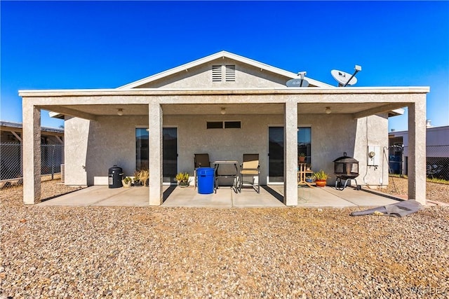 rear view of house with a patio area, fence, and stucco siding