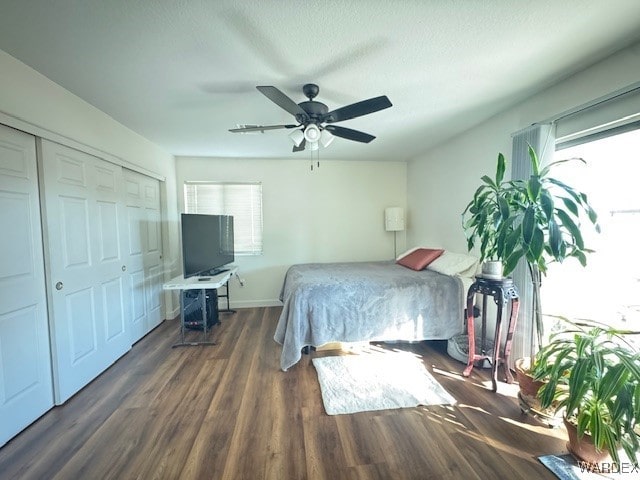 bedroom with dark wood-type flooring, a closet, baseboards, and a ceiling fan