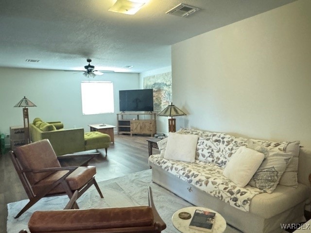 living room with ceiling fan, wood finished floors, and visible vents