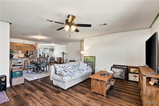 living room featuring dark wood-style flooring, visible vents, and ceiling fan