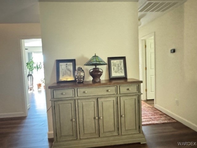 hall featuring baseboards, visible vents, and dark wood finished floors