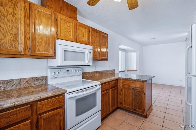 kitchen featuring light tile patterned floors, a peninsula, white appliances, and brown cabinetry