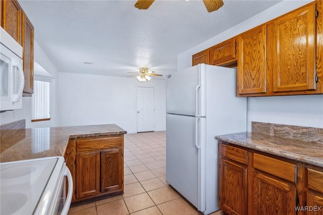 kitchen featuring white appliances, light tile patterned floors, ceiling fan, brown cabinets, and a peninsula