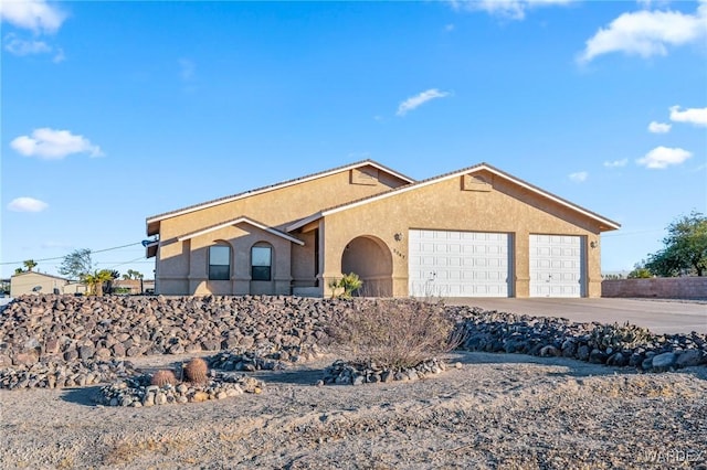 ranch-style home with a garage, driveway, and stucco siding