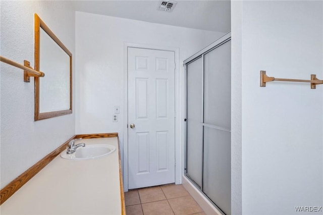 full bathroom featuring a shower stall, a sink, visible vents, and tile patterned floors