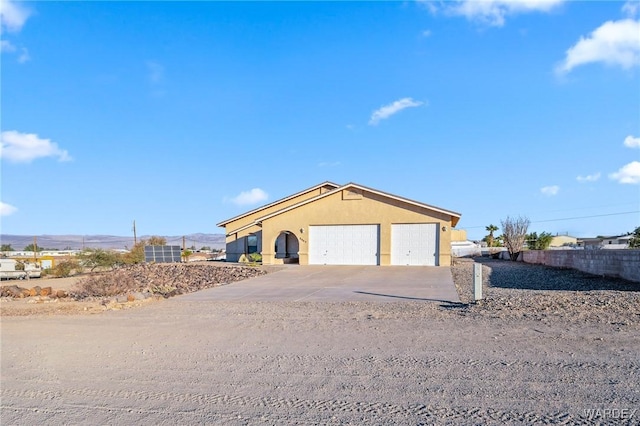 view of front facade featuring a garage, fence, concrete driveway, and stucco siding