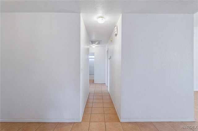 hallway featuring light tile patterned flooring, visible vents, and baseboards