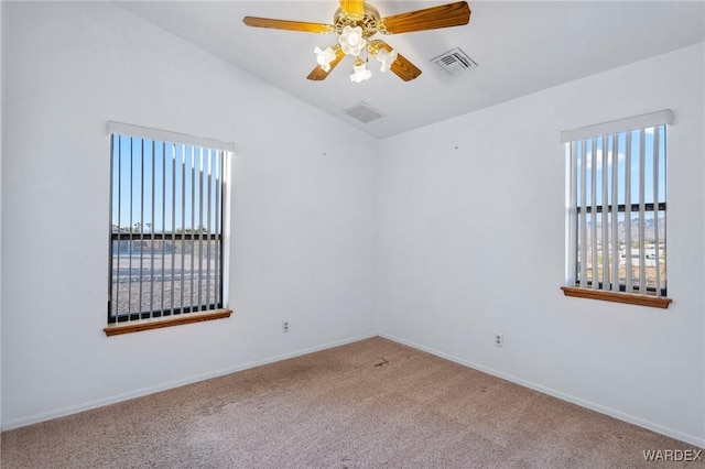 carpeted spare room featuring baseboards, visible vents, vaulted ceiling, and a ceiling fan