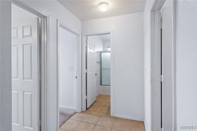 corridor with light tile patterned floors and baseboards