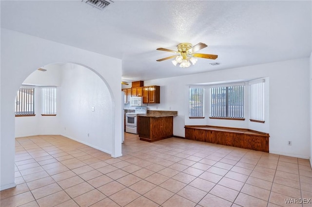 kitchen with white appliances, visible vents, ceiling fan, brown cabinets, and light countertops