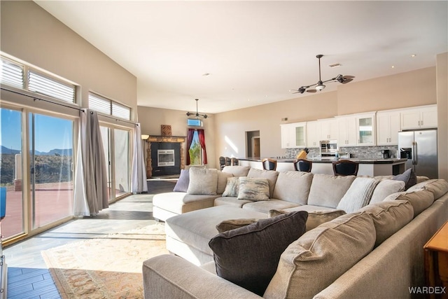 living room with visible vents, a towering ceiling, light wood-style floors, a glass covered fireplace, and a mountain view