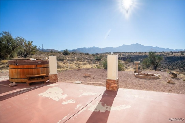 view of patio / terrace with a hot tub, fence, and a mountain view