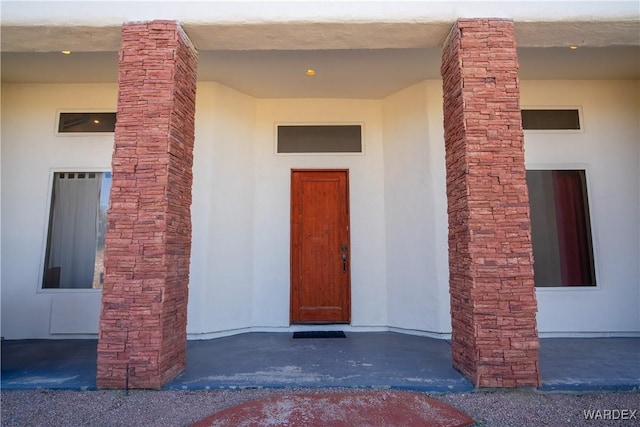 view of exterior entry featuring stone siding and stucco siding