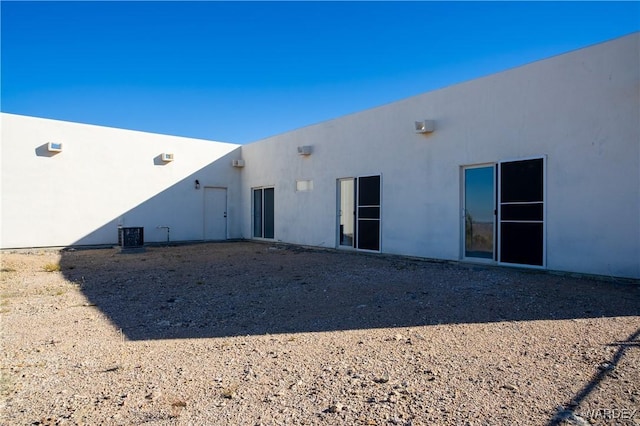 back of house with central air condition unit and stucco siding