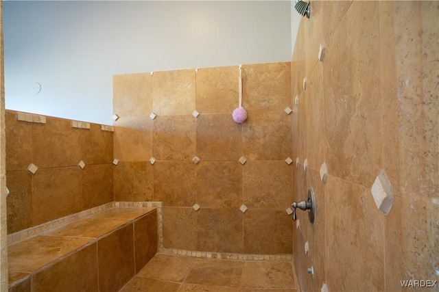 bathroom with a tile shower and tile walls