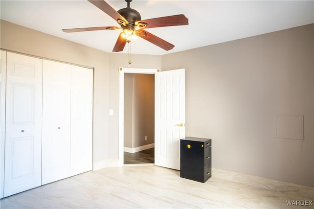 unfurnished bedroom with a ceiling fan, a closet, and baseboards