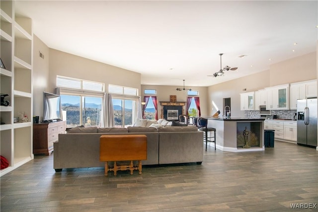 living area featuring dark wood-style floors, ceiling fan, and a glass covered fireplace