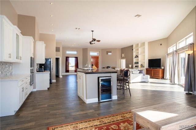 kitchen featuring dark wood-type flooring, wine cooler, open floor plan, and white cabinets