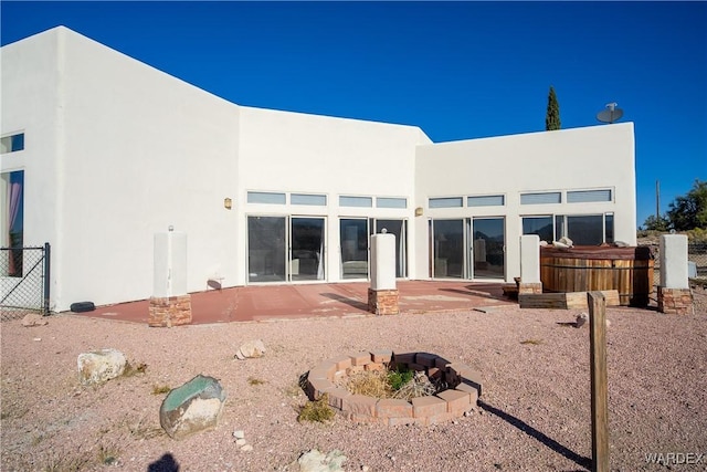 rear view of house featuring an outdoor fire pit, a patio area, and stucco siding