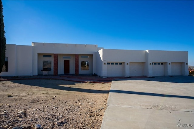 southwest-style home with driveway, an attached garage, and stucco siding