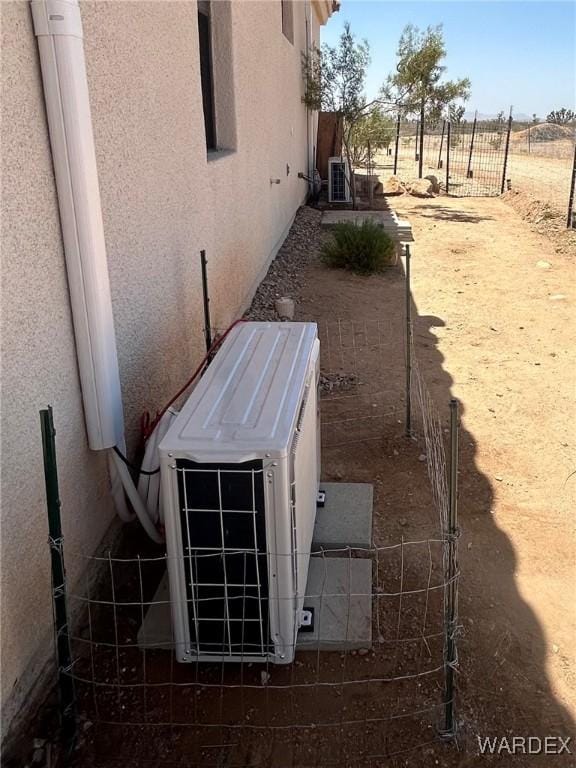 exterior details with ac unit, fence, and stucco siding