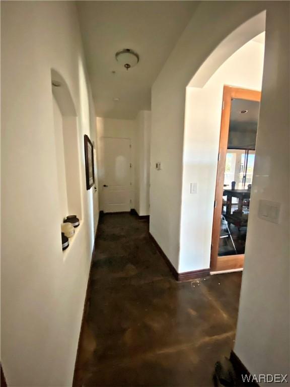 hall with concrete floors and baseboards