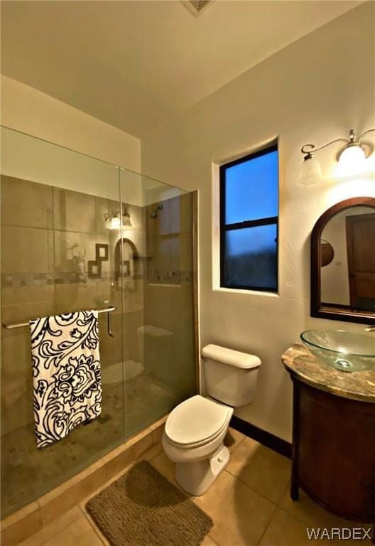 full bathroom featuring toilet, vanity, baseboards, tiled shower, and tile patterned floors