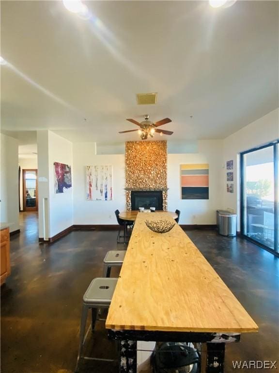 kitchen with concrete floors, ceiling fan, a fireplace, and baseboards