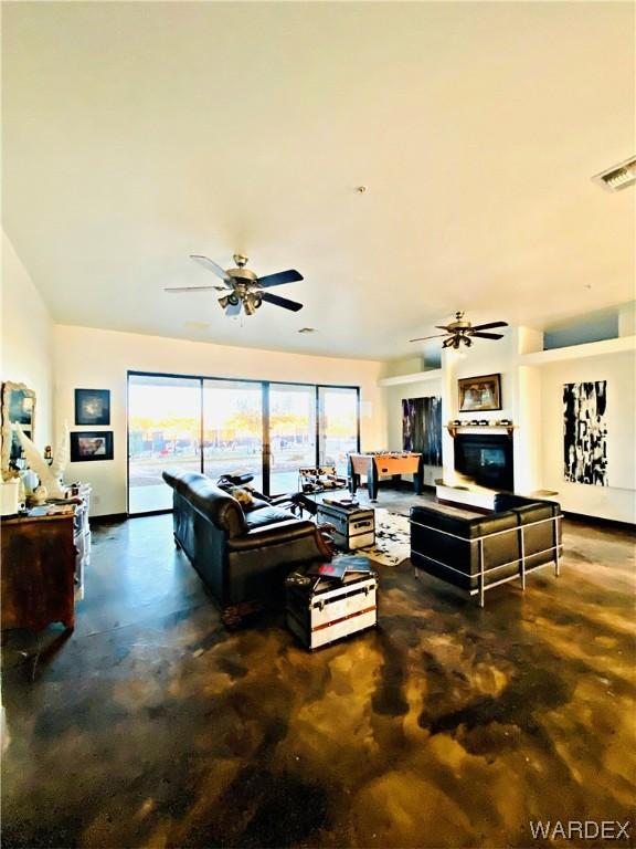 living room with ceiling fan, visible vents, and concrete flooring