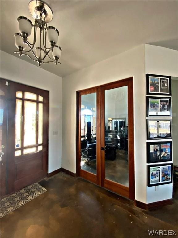 entryway featuring an inviting chandelier, concrete floors, baseboards, and french doors