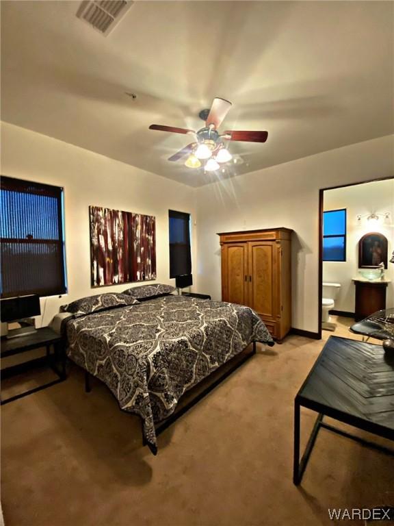 bedroom with baseboards, visible vents, a ceiling fan, light colored carpet, and ensuite bath