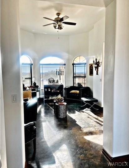 living area featuring concrete flooring and ceiling fan