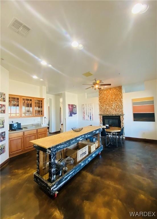 kitchen featuring glass insert cabinets, a fireplace, visible vents, and concrete flooring