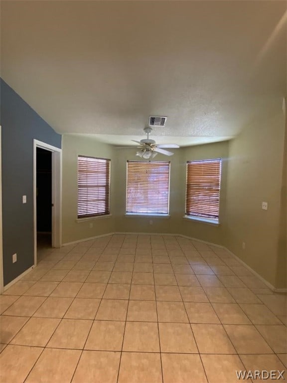 empty room with light tile patterned floors, visible vents, and a ceiling fan