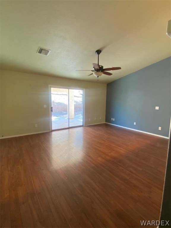 spare room with ceiling fan, dark wood-type flooring, visible vents, and baseboards