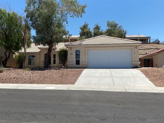 view of front of property featuring an attached garage, driveway, a tile roof, and stucco siding